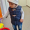 Dylan a rejoint le concours — aidez-le/la à gagner de superbes lots ! basketball_hoop, casual_clothing, child, curious, cute, door, exploring, floor, hallway, hat, indoor, jeans, knit_hat, play, shoes, standing, toddler, toy, vest, young_child