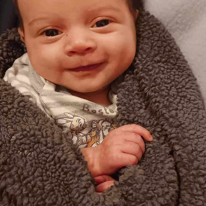 Bastian is registered to the contest to win money with this photo: baby, babylaughing, blanket, face, happy, head, newborn, person, photography, portrait, quilt, smile, towel, wool