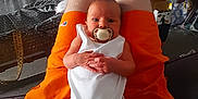 Rose joined the competition — help win amazing prizes! baby, pacifier, person, legs, orange_shorts, white_onesie, living_room, television, furniture, couch, carpet, basket, clothing, indoor, home, child, sitting, hands, face, relaxation