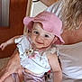 Gabie a rejoint le concours — aidez-le/la à gagner de superbes lots ! baby, child, pink_hat, smiling, indoor, person, white_clothing, holding, cute, happy, shorts, seated, hand, face, headwear, casual, people, skin, portrait, infant