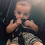 baby, child, stroller, seatbelt, curious, wide_eyes, hand, clothing, shorts, sitting, indoor, candid, infant, cute, closeup, skin, baby_boy, comfortable, sunlight, black_strap