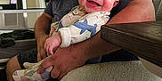 James is registered to the contest to win money with this photo: baby, adult, beard, smile, indoor, chair, person, clothing, furniture, hand, happy, carpet, table, sitting, home, sleeve, skin, face, background, cozy