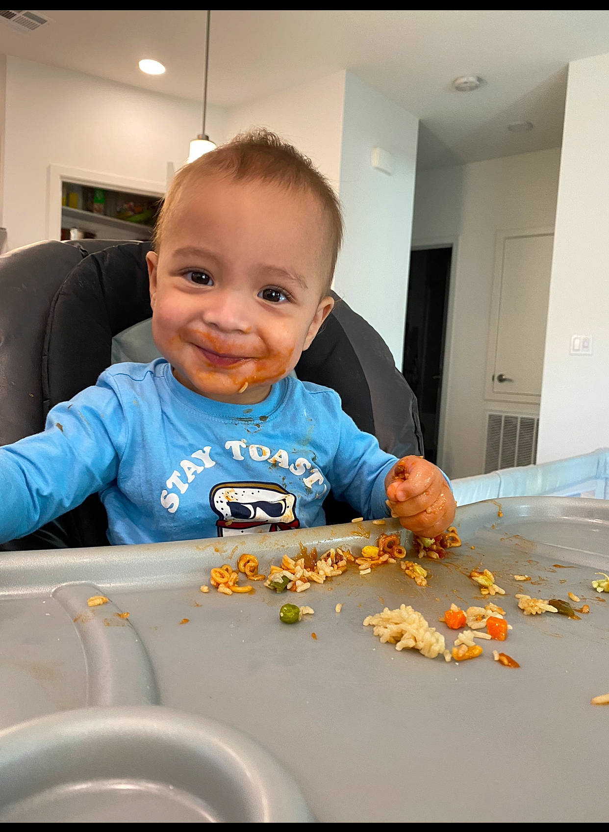 Cassius is registered to the contest to win money with this photo: baby, baby_toddler_clothing, chair, child, comfort, comfort_food, door, finger, flooring, fun, happy, joy, orange, person, room, sitting, sleeve, smile, sweetness, t_shirt