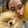 Dolce a rejoint le concours — aidez-le/la à gagner de superbes lots ! dog, puppy, pomeranian, fluffy, cream_colored, small_dog, person, woman, portrait, selfie, cuddling, holding, glasses, closed_eyes, indoor, warm_lighting, gray_sweater, hand, cute, pet