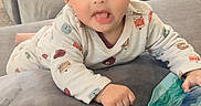 Rayshan is registered to the contest to win money with this photo: baby, child, infant, hat, onesie, animal_print, couch, sofa, pillow, indoor, toy, inflatable, curious, lying_down, cozy, cute, face, hand, expression, soft_furniture