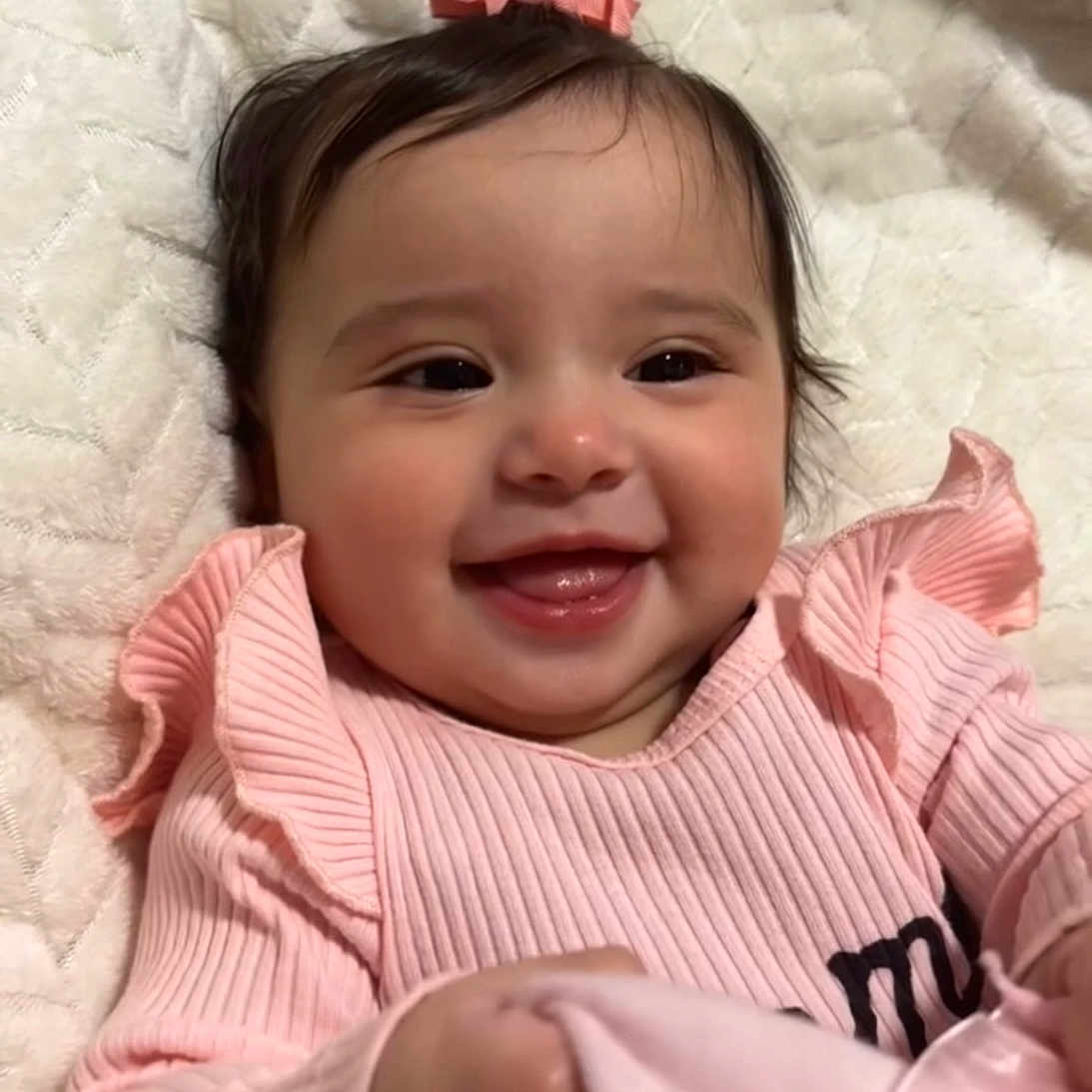 Jaylani is registered to the contest to win money with this photo: baby, blanket, child, closeup, clothing, cozy, cute, face, girl, hand, happy, indoor, infant, person, pink_bow, pink_sweater, portrait, smiling, soft_texture, toddler