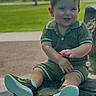toddler, child, outdoor, park, rock, greenery, grass, sky, clouds, sneakers, shorts, polo_shirt, smiling, happy, sitting, daylight, nature, casual_clothing, cute, young_child