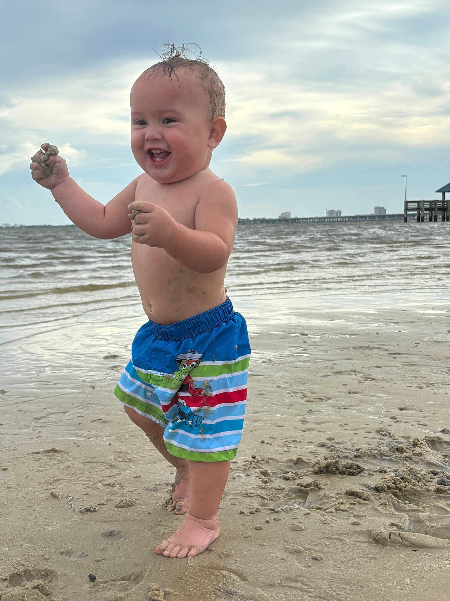 Waylon joined the competition — help win amazing prizes! toddler, child, beach, sand, water, ocean, waves, cloudy_sky, barefoot, swim_shorts, happy, playing, smiling, outdoor, summer, nature, fun, wet_sand, person, shore