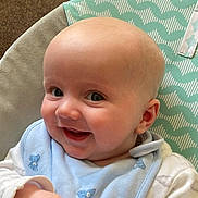 Logan is registered to the contest to win money with this photo: baby, smiling, face, blue_bib, infant, child, cute, patterned_cushion, happy, closeup, skin, eyes, cheeks, clothing, portrait, indoor, baby_bib, baby_clothing, head, expression