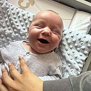 Theo is registered to the contest to win money with this photo: baby, smiling, infant, hand, blanket, clothing, person, face, cute, happy, newborn, texture, indoor, skin, fingernails, cozy, closeup, expression, toddler, comfort