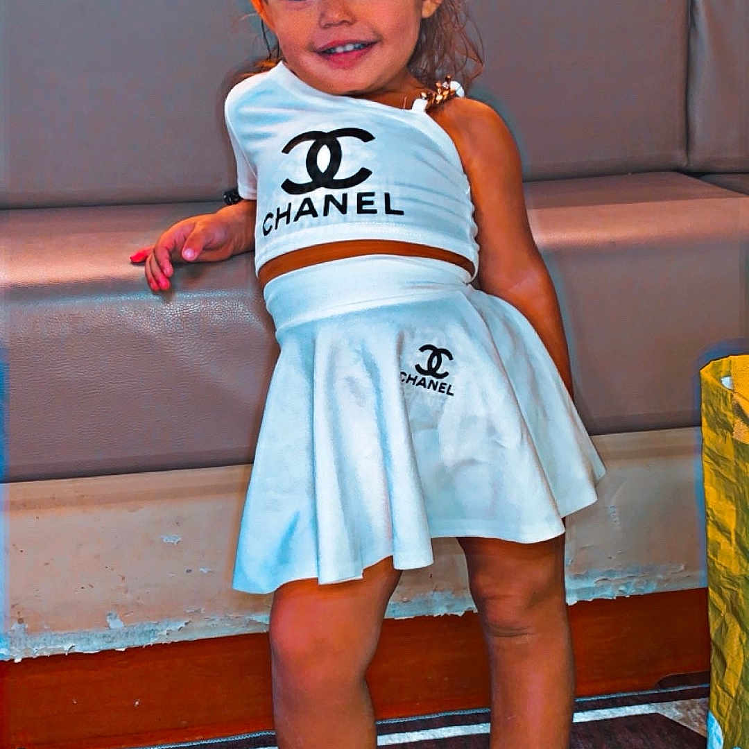 Inaya a rejoint le concours — aidez-le/la à gagner de superbes lots ! bench, boots, carpet, chanel, child, cute, fashion, floor, footwear, girl, hair_tied, happy, indoor, person, portrait, pose, smile, stylish, white_clothing, young