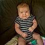 Hudson is registered to the contest to win money with this photo: baby, infant, child, couch, blanket, striped_clothing, onesie, fist, chubby_cheeks, smirk, indoor, person, seated, furniture, cute, expression, cozy, soft_texture, skin, young