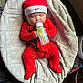baby, bottle, red_clothing, hat, blanket, sleeping, infant, person, footed_pajamas, indoor, cute, resting, child, feeding, cozy, soft_texture, newborn, relaxing, sleep, comfort