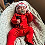 baby, infant, pacifier, red_clothing, nike_logo, blanket, bed, sleeping, fist, footed_pajamas, hat, indoors, person, cute, newborn, soft_texture, relaxation, cozy, peaceful, lying_down