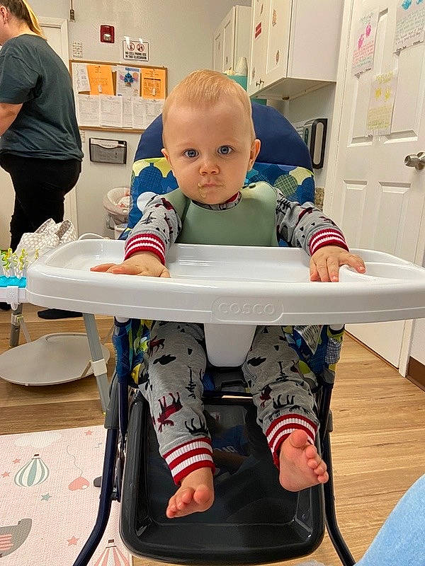 Greyson is registered to the contest to win money with this photo: baby, barefoot, carmine, child, foot, human_leg, knee, learning, luggage_and_bags, person, play, room, shelf, shelving, shorts, sitting, sportswear, t_shirt, table, thigh