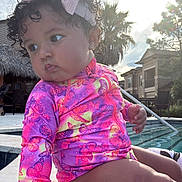 Aslhey Melanie joined the competition — help win amazing prizes! toddler, child, swimsuit, bow, curly_hair, poolside, water, outdoor, sunlight, sky, clouds, palm_tree, residential, hand, legs, face, earrings, colorful_clothing, marble_floor, summer