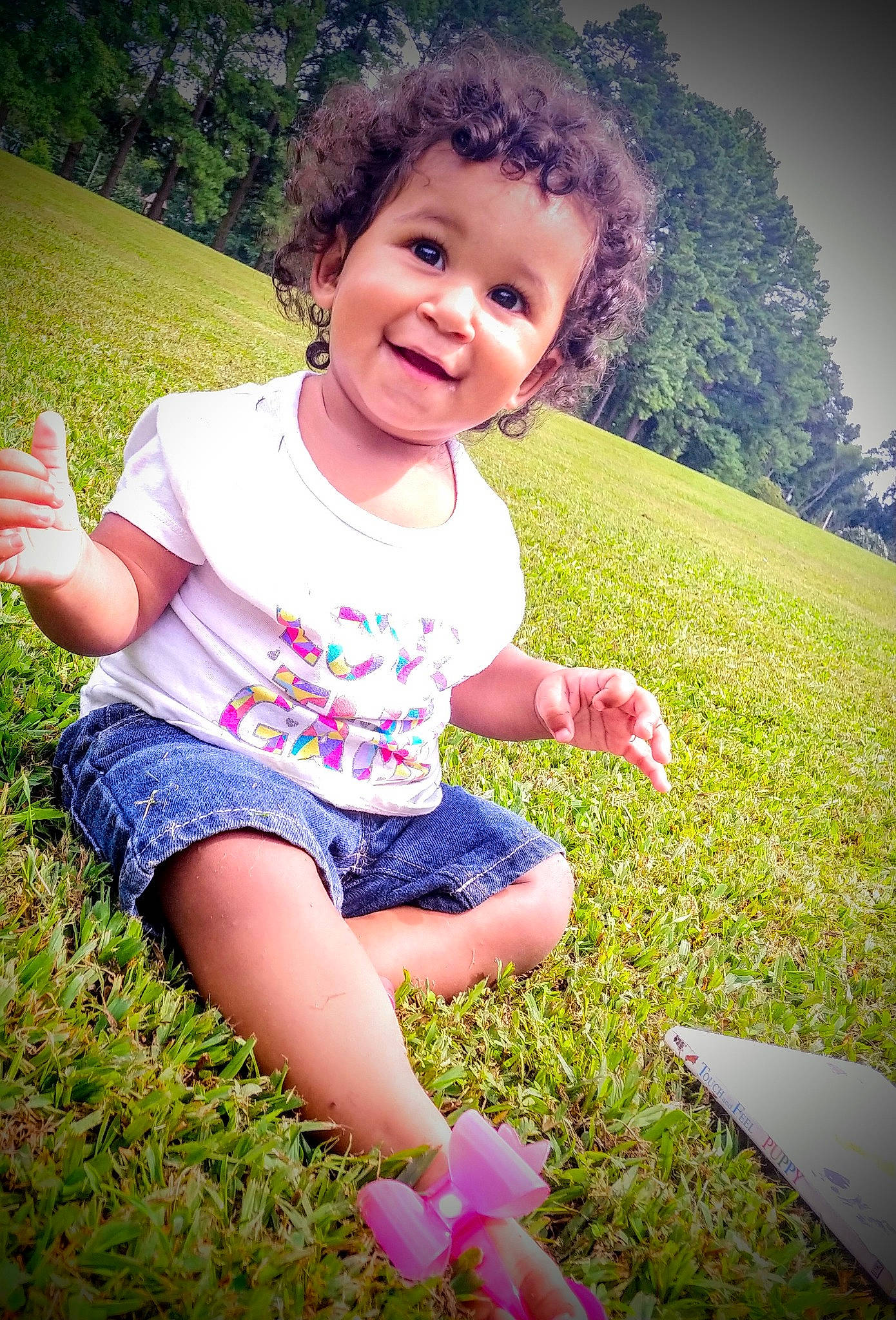 Carmella is registered to the contest to win money with this photo: child, facial_expression, finger, fun, grass, grass_family, green, happy, joy, meadow, people, people_in_nature, person, pink, plant, play, sitting, skin, smile, summer