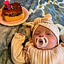 baby, pacifier, birthday_cake, candle, blanket, knit_clothing, headband, infant, celebration, lying_down, soft_texture, closeup, cute, indoor, child, one_year, warm_colors, sleepy, small_cake, festive