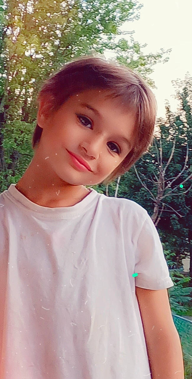 Bobby is registered to the contest to win money with this photo: bangs, child, cool, eye, forehead, grass, hairstyle, happy, joy, lip, neck, person, pink, plant, shoulder, sleeve, smile, standing, summer, sunlight