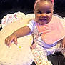 baby, child, smiling, headband, pink_bib, cushion, floral_pants, sitting, indoors, happy, cute, infant, clothing, person, face, foot, hand, blanket, bed, comfort