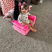 Leo joined the competition — help win amazing prizes! toddler, child, pink_chair, plush_chair, pillow, carpet, living_room, toy, smiling, cute, indoors, person, furniture, colorful, happy, seat, cozy, pattern, hair, face