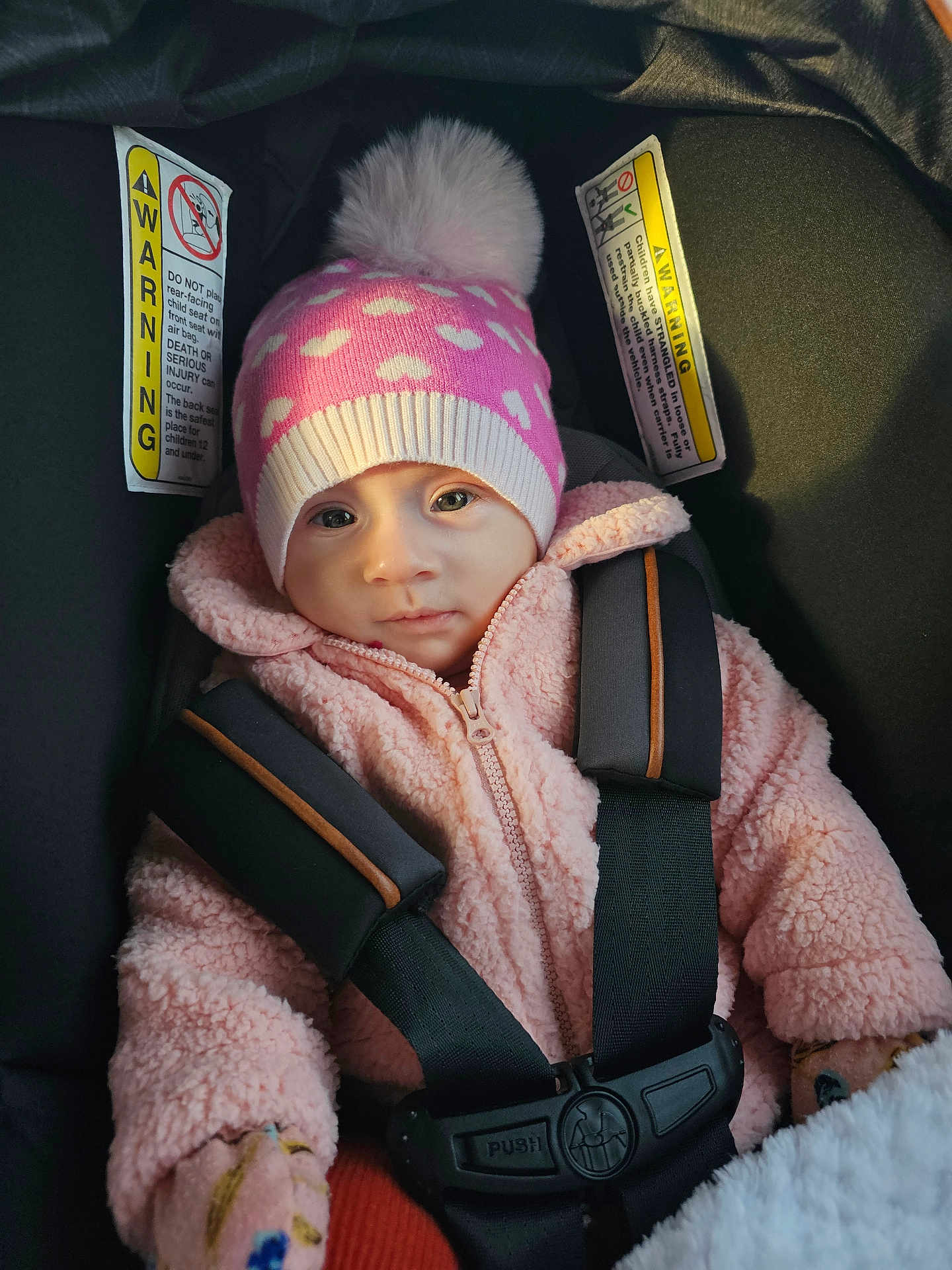 Selma joined the competition — help win amazing prizes! baby, infant, child, car_seat, beanie, pom_pom, pink_jacket, harness, buckle, warning_label, seat_belt, portrait, closeup, cozy, mittens, soft_texture, wide_eyed, face, winter, bundle