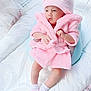 Ayzal Furqan is registered to the contest to win money with this photo: baby, pink, bathrobe, hat, socks, slippers, bow, cushion, soft, white, indoors, child, infant, cute, cozy, resting, portrait, clothing, comfortable, curious
