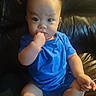 baby, child, blue_clothing, sitting, finger_in_mouth, curious, leather_couch, indoors, infant, portrait, cute, chubby, young_child, casual, one_person, human, skin, short_hair, seated, expression