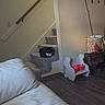 Binx is registered to the contest to win money with this photo: bag, black_cat, carpet, cat, corner, couch, decor, floor, furniture, handrail, indoor, living_room, pet, pet_bowls, red_bowls, stairs, television, wall, white_couch, wood_floor