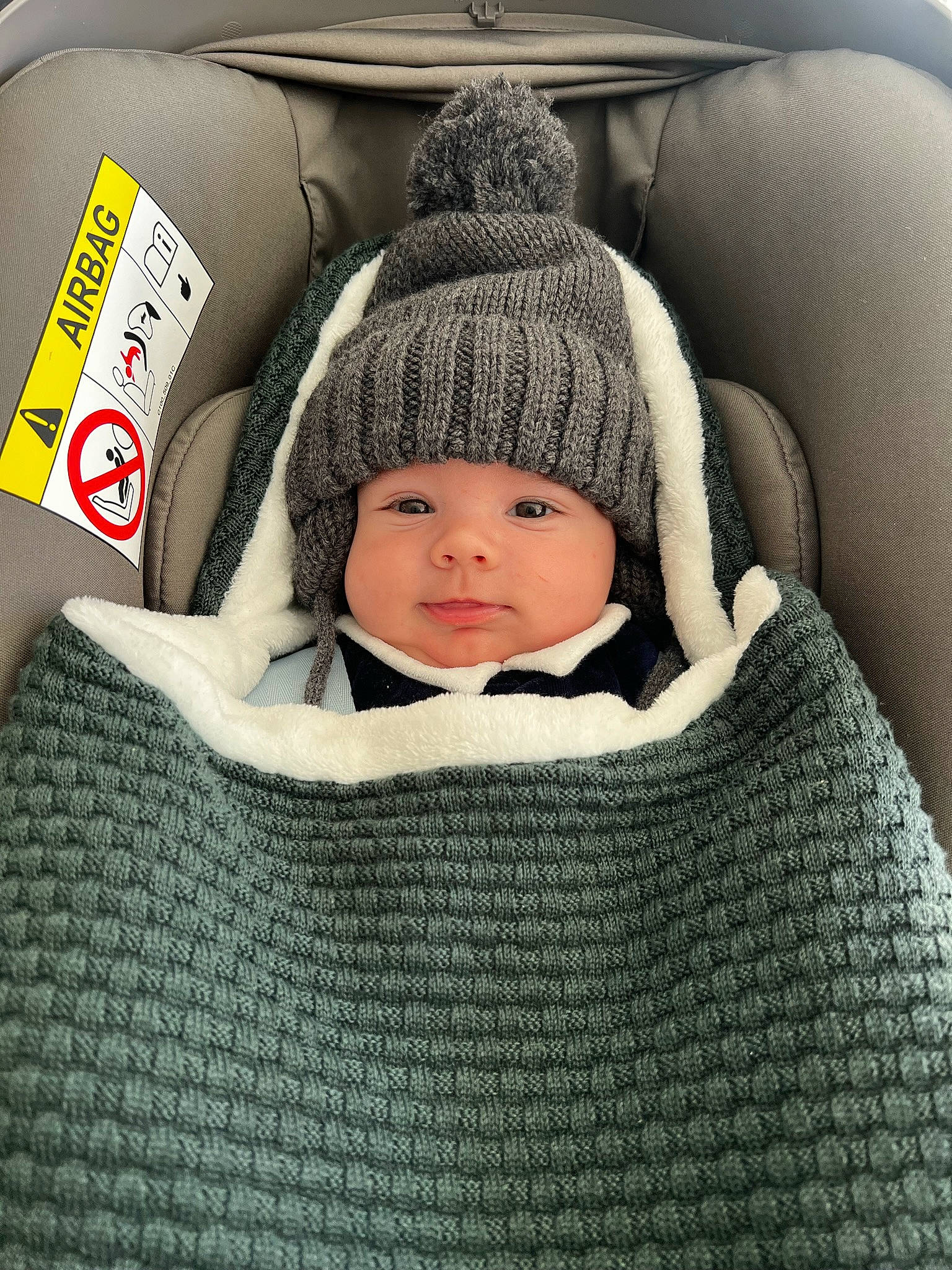 Hugo a rejoint le concours — aidez-le/la à gagner de superbes lots ! baby, baby_toddler_clothing, beanie, cap, car_seat, cheek, child, comfort, face, fashion_accessory, headwear, knit_cap, linens, pattern, person, sitting, sleeve, toddler, winter, wool