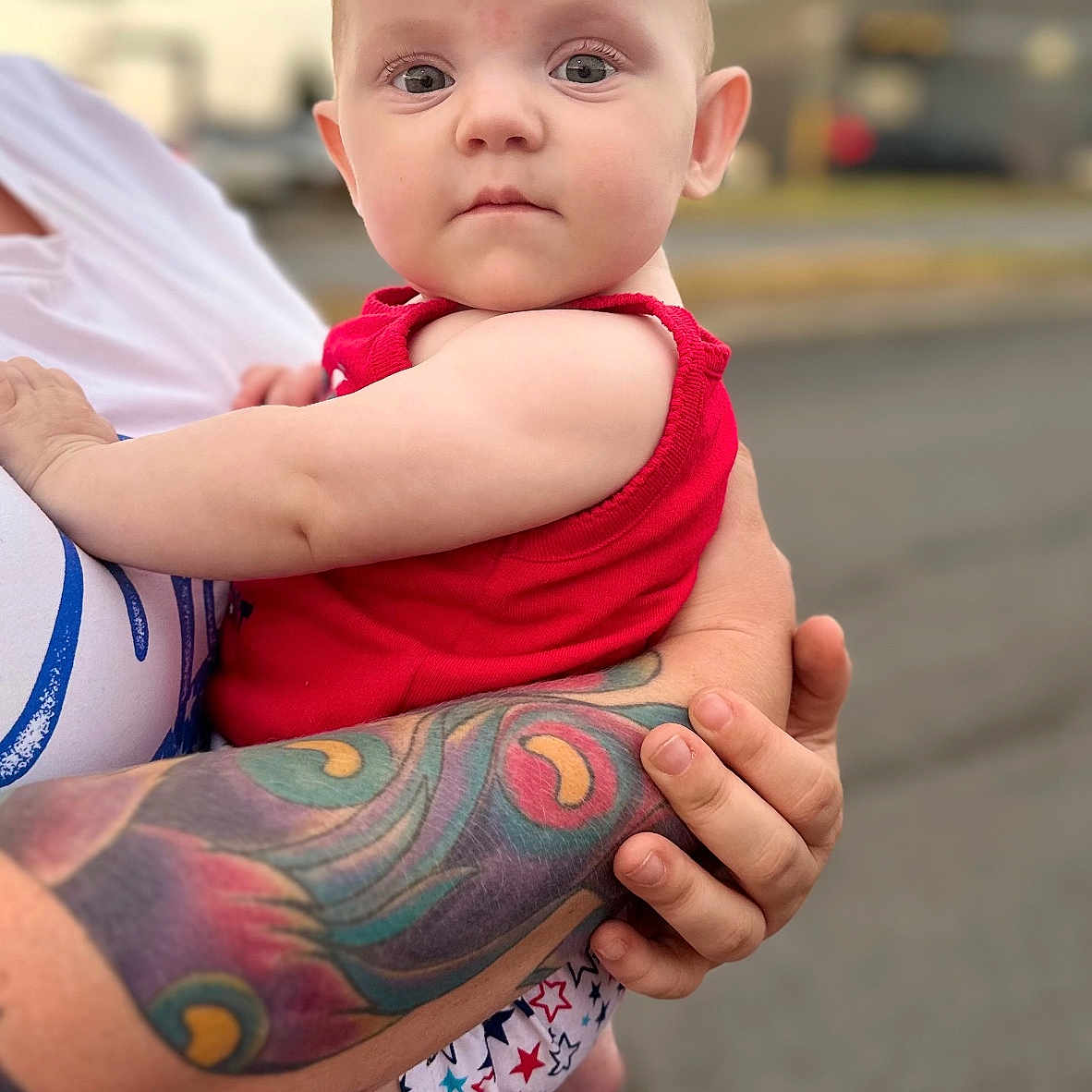 Paislee is registered to the contest to win money with this photo: accessories, arm, baby, bodypart, clothing, face, finger, hand, head, hugging, newborn, pants, person, photography, portrait, shorts, skin, t_shirt, tattoo, wrist