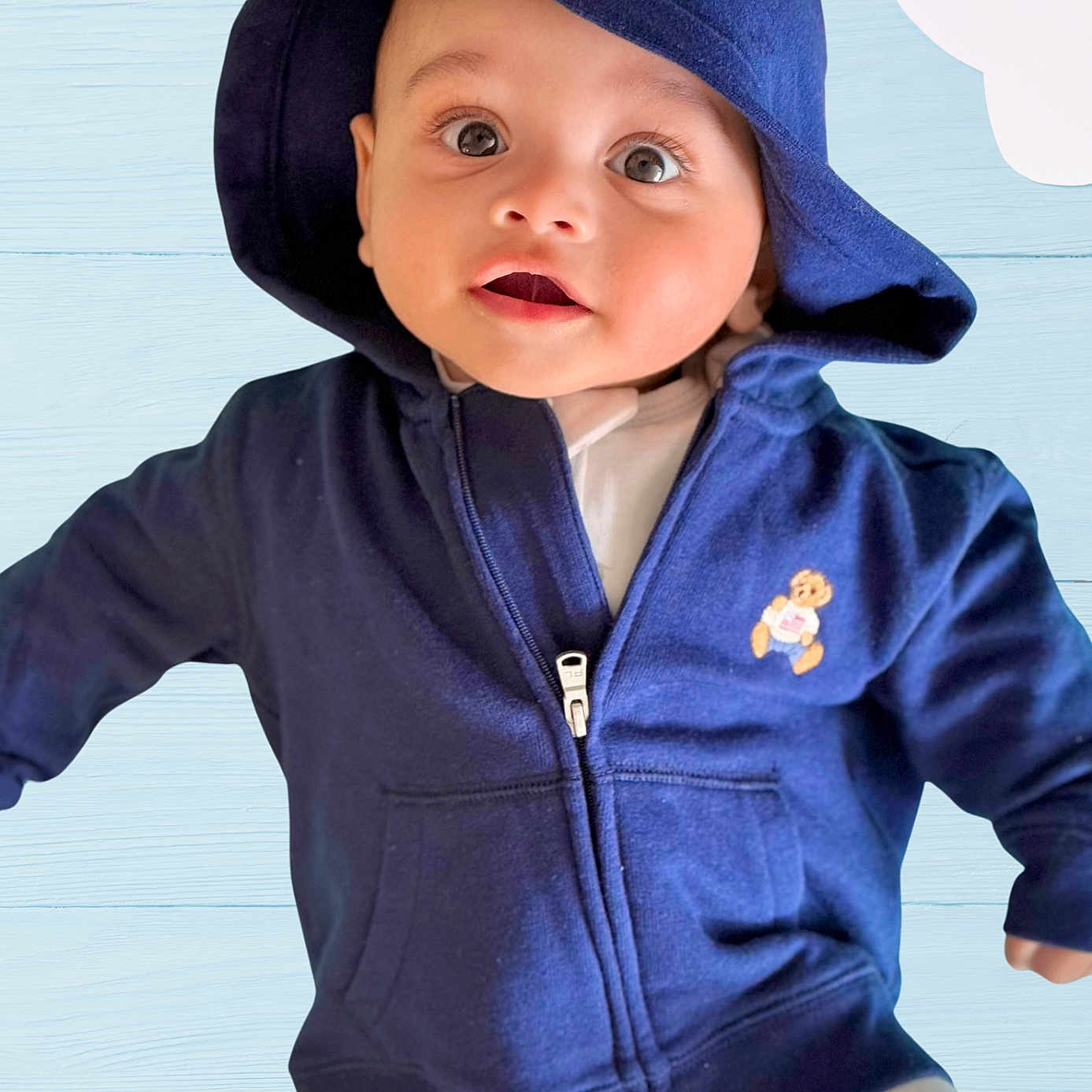 Swayam joined the competition — help win amazing prizes! apparel, baby, babywear, background, blue_clothing, child, clothing, cute, cute_expression, eyes, fabric, face, headwear, hoodie, indoor, infant, person, portrait, smiling, young_child