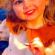 Lesly a rejoint le concours — aidez-le/la à gagner de superbes lots ! child, girl, smile, face, eyes, dress, collar, hand, indoor, warm_light, happy, cute, portrait, young, person, clothing, hair, candid, childhood, sunlight