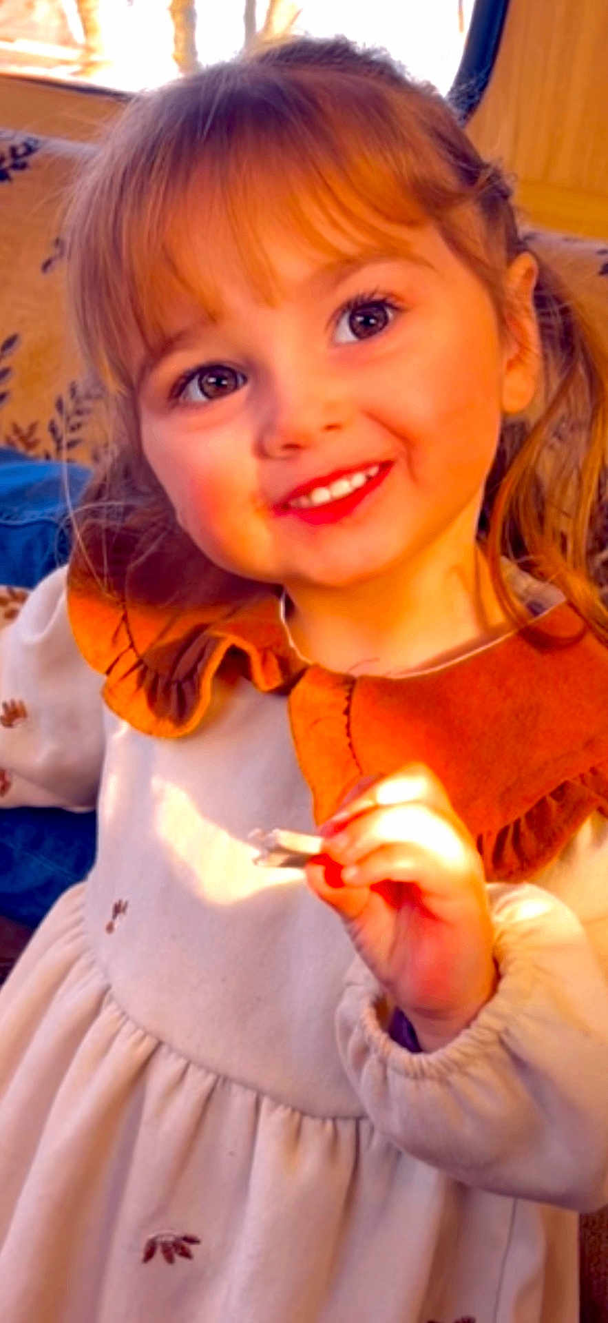 Lesly a rejoint le concours — aidez-le/la à gagner de superbes lots ! child, girl, smile, face, eyes, dress, collar, hand, indoor, warm_light, happy, cute, portrait, young, person, clothing, hair, candid, childhood, sunlight