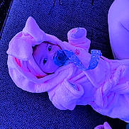 Nova is registered to the contest to win money with this photo: baby, pacifier, pink_bunny_outfit, fluffy_clothing, infant, lying_down, soft_texture, hand, tattoo, closeup, cute, child, indoors, face, expression, cozy, clothing, person, resting, babywear