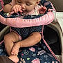 baby, high_chair, infant, child, indoor, pink, navy_blue, floral_pattern, clothing, person, seat, cute, playing, smiling, fingers, legs, feet, skin, head, face