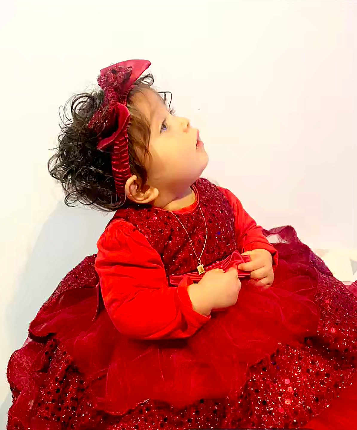 Loriana participe au concours pour gagner de l'argent avec cette photo : celebration, child, curly_hair, cute, dress, fashion, hands, headband, holiday_outfit, indoor, innocence, jewelry, looking_up, necklace, portrait, red_dress, side_profile, sparkles, toddler, young_child