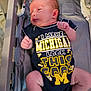 Freyja is registered to the contest to win money with this photo: baby, infant, crib, onesie, clothing, text, blue, yellow, newborn, person, skin, hair, hand, leg, bed, michigan, cute, indoor, soft_light, sleeping_area
