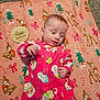 baby, infant, pink_onesie, snowman_pattern, blanket, deer_pattern, wooden_plaque, five_months, carpet, milestone, cute, lying_down, indoors, holiday_theme, child, face, hand, clothing, soft_texture, portrait