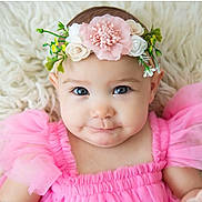 Delaney is registered to the contest to win money with this photo: baby, infant, child, portrait, face, smiling, lying_down, pink_dress, floral_headband, flowers, blanket, fluffy_texture, indoor, close_up, blue_eyes, fashion, cute, photography, soft_lighting, toddler