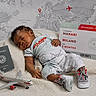 baby, sleeping, infant, blanket, toy_airplane, passport, boarding_pass, map, world_map, sneakers, travel, travel_theme, child, resting, indoor, cute, clothing, hand, face, napping