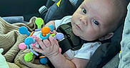 Waylon joined the competition — help win amazing prizes! baby, infant, car_seat, toy, colorful, blanket, child, seatbelt, indoors, cute, person, holding, small_hands, car_interior, safety, portrait, looking_at_camera, head_support, clothing, newborn