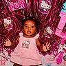 baby, child, infant, portrait, lying_down, smiling, curious, pink_dress, hello_kitty, balloons, party_decoration, tinsel, plush_toy, toy, bow, letter, pink, colorful, indoor, celebration