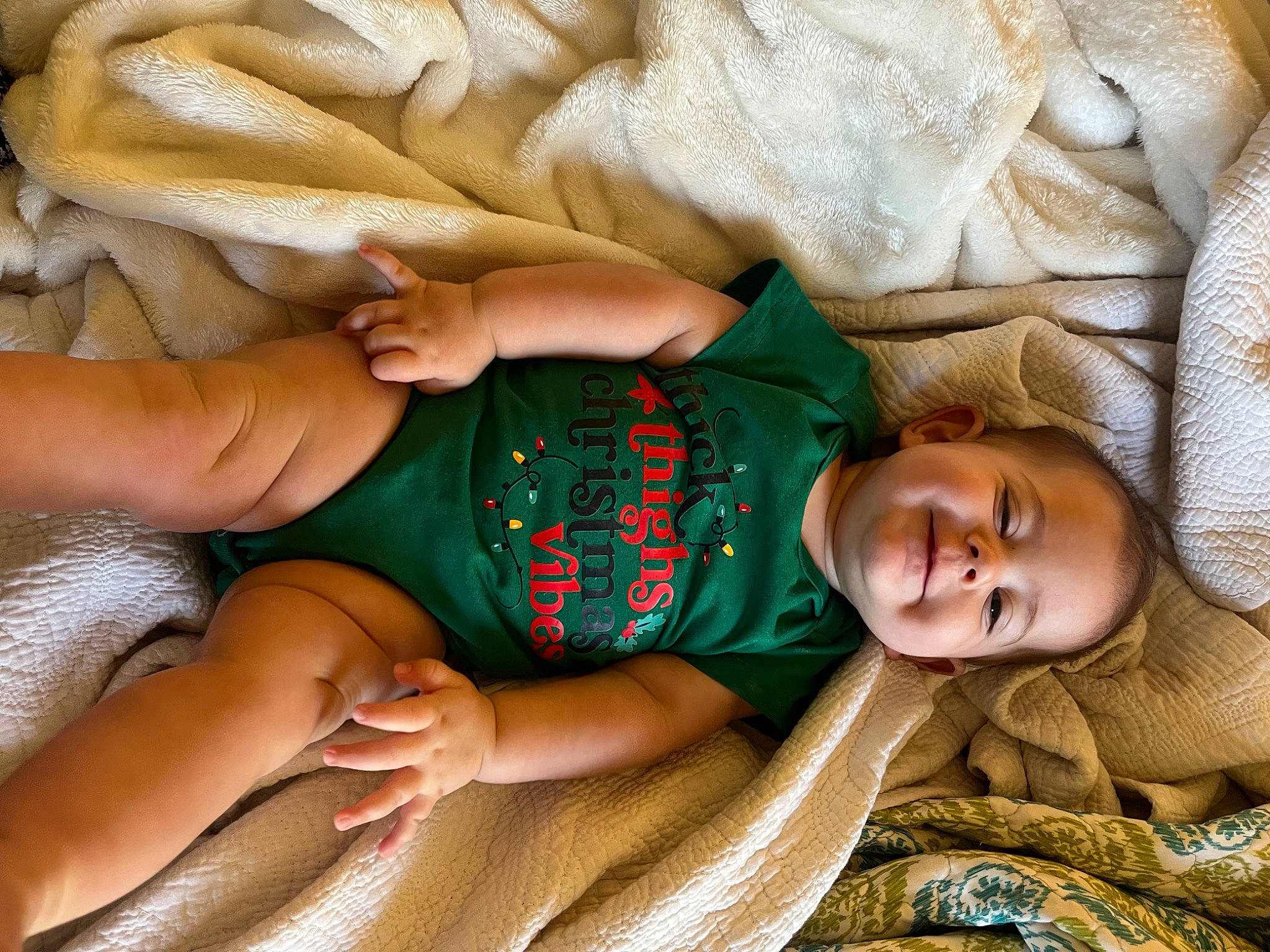 Camryn is registered to the contest to win money with this photo: abdomen, baby, child, comfort, couch, finger, hand, happy, human_body, human_leg, leg, linens, pattern, person, sitting, skin, smile, thigh, toddler, trunk
