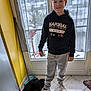Hugo participe au concours pour gagner de l'argent avec cette photo : boy, child, dog, indoor, window, curtain, snow, floor, tile, sneakers, hoodie, pants, door, toy, pet, animal, casual_clothing, red_scooter, yellow_wall, home