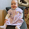 baby, child, smile, dress, lavender, chair, indoors, cute, happy, sitting, face, person, cozy, furniture, tights, bow, embroidery, home, soft_lighting, pet_bed