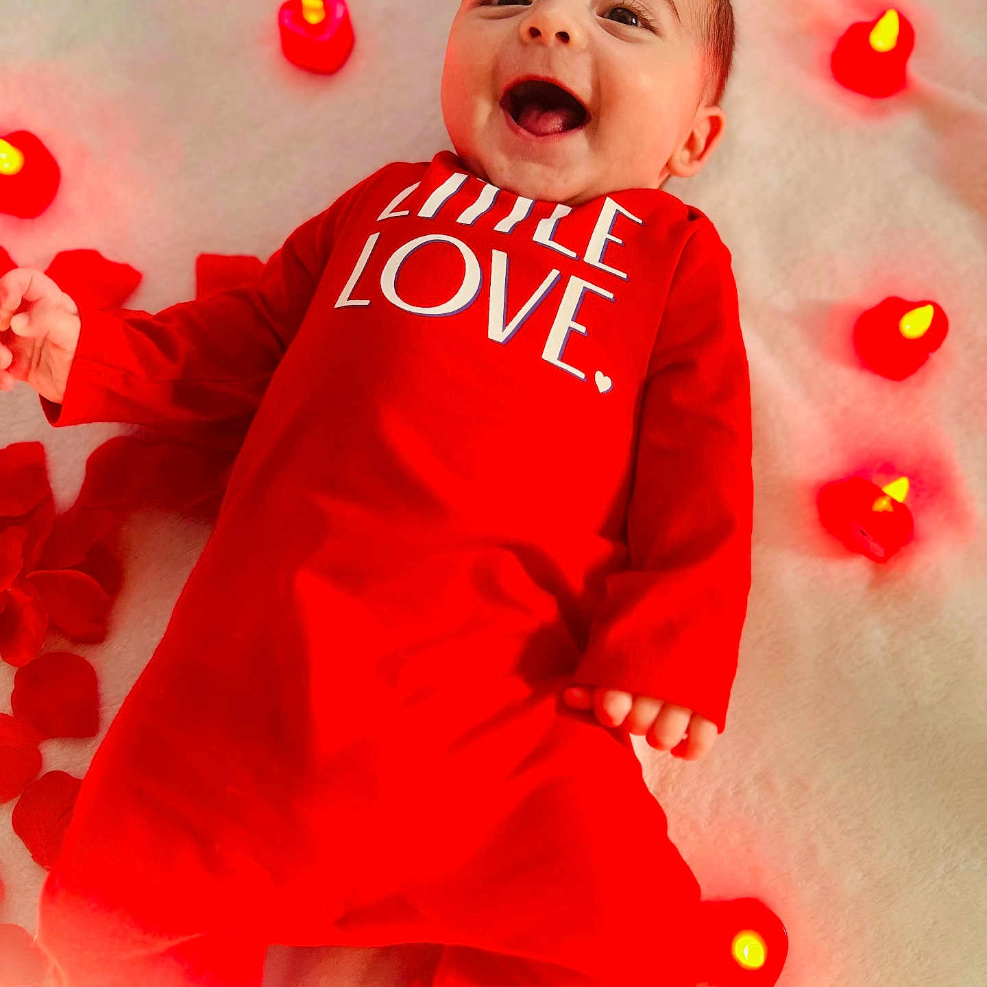 Landon is registered to the contest to win money with this photo: baby, babylaughing, blanket, candle, clothing, dress, face, flower, happy, head, laughing, lighting, pajamas, person, petal, photography, plant, portrait, smile, yawning