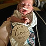 Everest joined the competition — help win amazing prizes! baby, infant, two_months, blanket, clothing, face, person, hospital_tube, nasal_tube, wooden_sign, tongue_out, wrapped, soft_fabric, lying_down, cute, newborn, indoors, closeup, medical, resting