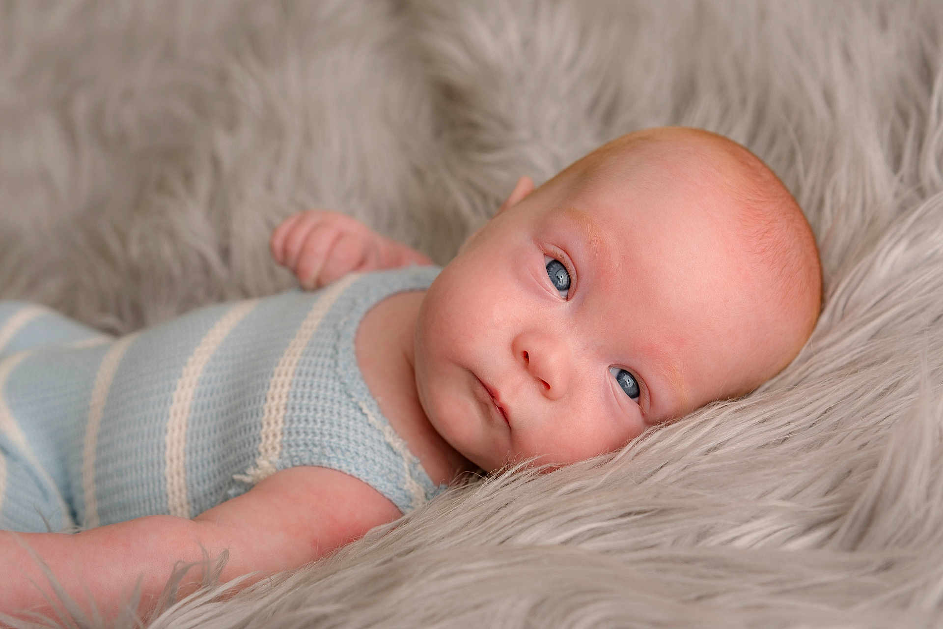 Everest is registered to the contest to win money with this photo: baby, infant, blue_eyes, knitted_clothing, striped_outfit, lying_down, fluffy_blanket, soft_texture, close_up, portrait, cute, newborn, skin, head, face, arm, resting, cozy, indoor, child