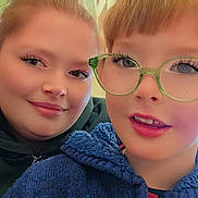 Toby Dickinson is registered to the contest to win money with this photo: child, person, glasses, smile, face, portrait, indoor, young, red_hair, green_hoodie, blue_sweater, close_up, happy, eyewear, casual_clothing, light, window, friendship, family, together